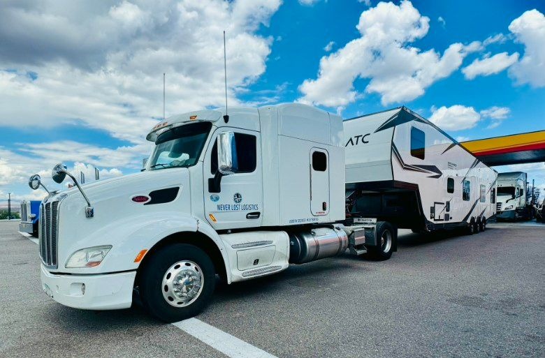 A Never Lost Logistics tractor hooked to a travel trailer at a fuel stop before a long desert run