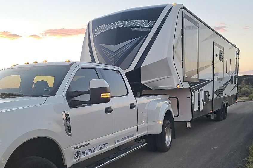 A Never Lost Logistics dually and a Momentum toy hauler fifth wheel at sunset